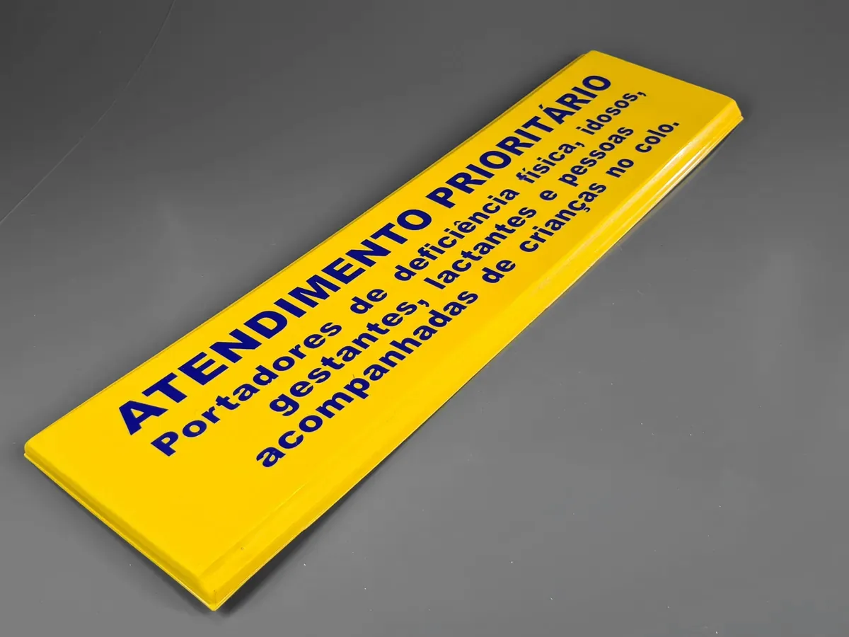 Placa de sinalização de atendimento prioritário, em amarelo com texto em relevo
